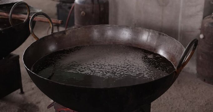 Large batch hot cooking oil preparation for event catering, ideal for frying puri and boondi in a traditional Indian kitchen setup