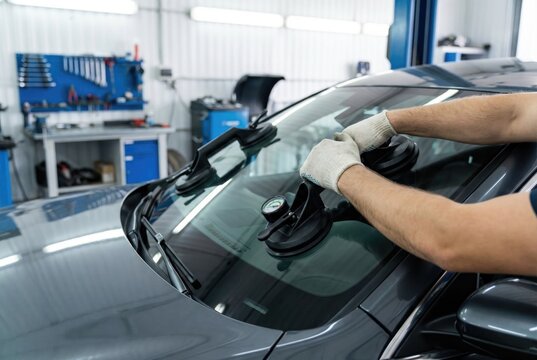 Auto mechanic attaching heavy duty suction cups to car windshield for replacement