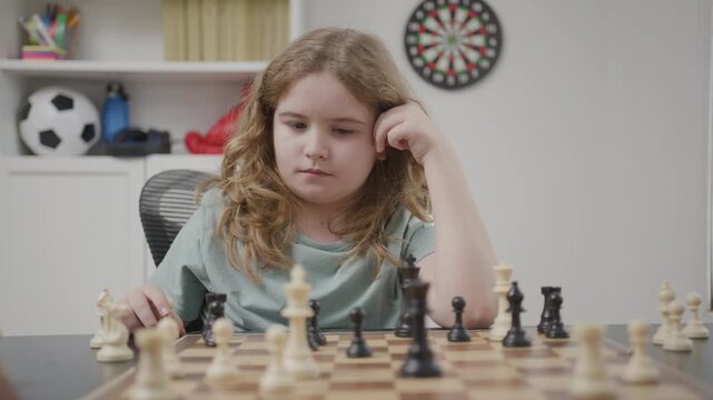 Child improving concentration through chess game. Kid studying chess moves at table. Child learning problem solving with chess. Kid planning next chess move.