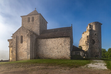 Obraz premium Cornil (Corrèze, Nouvelle aquitaine, France) - Vue matinale brumeuse des ruines du donjon du château de la Chapoulie et l'église de l'invention des reliques de Saint Etienne