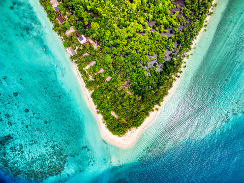 Aerial view of Sipura Island featuring lush tropical forests, white sandy beaches, and vibrant coral reefs surrounded by turquoise ocean waters in Mentawai Islands Regency, West Sumatra, Indonesia.