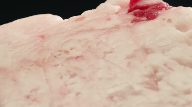 Raw lamb sheep fat tail fat on wooden board, close up of middle eastern pork or lamb dish. Rotating macro meat. 