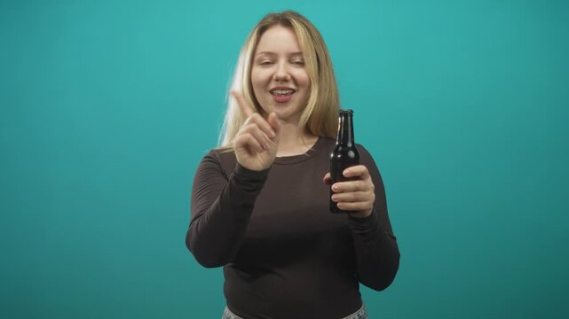 Woman points finger while holding beer bottle with visible hand and smirk in studio; playful teasing.