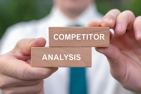 Concept for market, competitors and customers analysis. Business person holding wooden blocks sees the inscription COMPETITOR ANALYSIS.