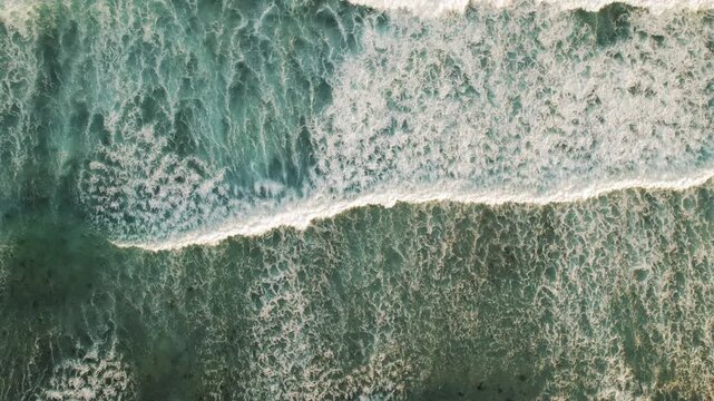 Top down view of ocean waves powerful surf crashing over shallow reef at dusk