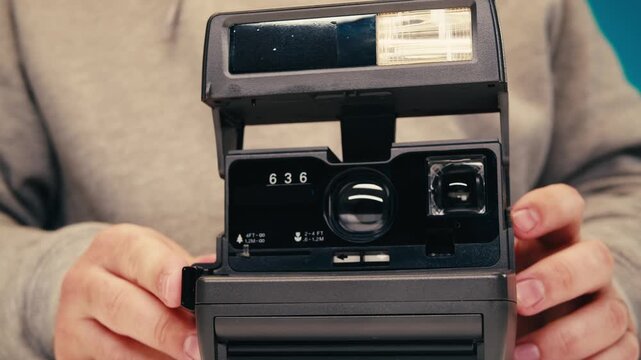 Vintage black instant photo camera, man touching and using retro old photo device, photographer Summer travel concept. Equipment for capturing moments