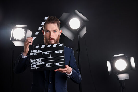 Professional actor in suit with clapperboard on stage