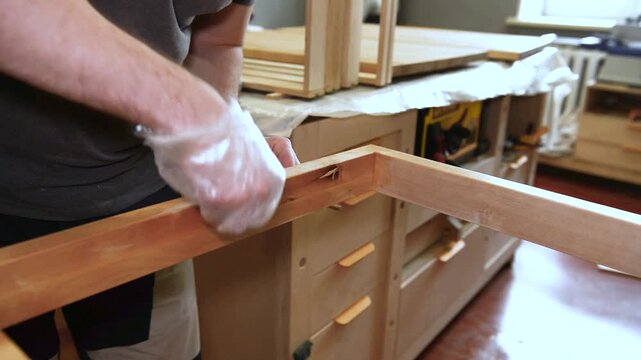 Master carpenter, Applying natural oil on natural wood product. Hand applying wood protection oil on boards with rags. Hand applying wood protection piece in gold color with rags, indor.