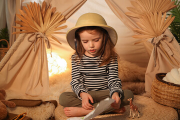 Little girl with drawing of map near wigwam at home © New Africa