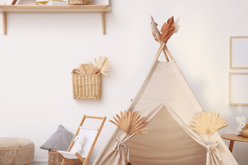 Stylish wigwam with dry leaves in child's room. Space for text © New Africa