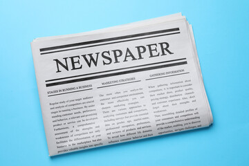 Fototapeta premium Folded newspaper on light blue background, top view