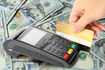 Woman using payment terminal and credit card on dollar banknotes, closeup © New Africa