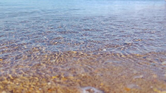 sunrice seashore with wave close up. Calm morning ocean water waves splashing sandy beach. Closeup sea relax waves breaking sand beach at summer morning. slow motion. nature background travel relax. n