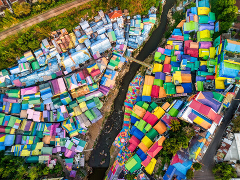 Aerial view of the vibrant multi-colored rooftops and narrow river of Kampung Warna Warni Jodipan in Kecamatan Blimbing, Jawa Timur, Indonesia.