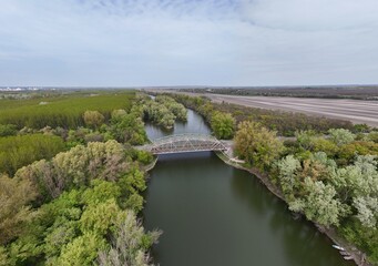 Fototapeta premium Aerial view of bridge over river oxbow with lush green landscape