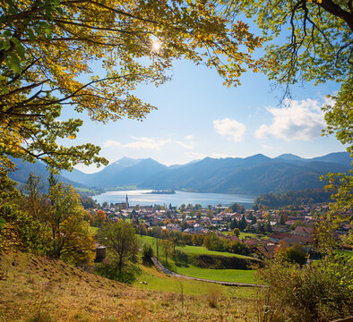 beautiful view to lake and tourist resort schliersee. framed by autumnal branches