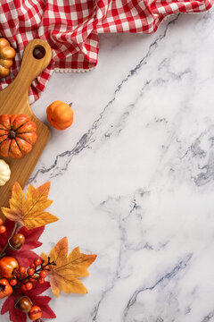 Autumn kitchen cooking vertical scene with pumpkin decor on cutting board and marble countertop for recipe preparation