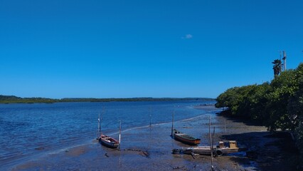 Obraz premium Boats Anchored On Muddy Shore Under Blue Sky