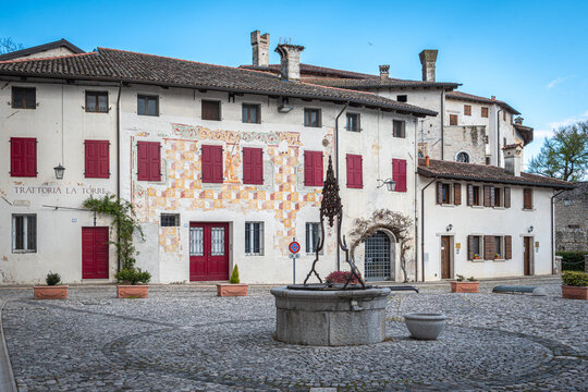 Piazza Castello in Valvasone with the ancient stone well and historic buildings decorated with Renaissance frescoes, Friuli Venezia Giulia, Italy