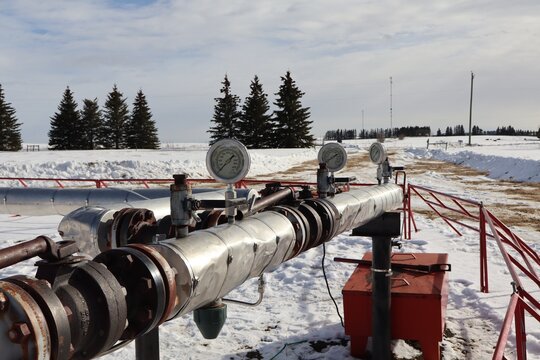 This shows an industrial insulated pipeline system, used for oil or natural gas transmission in a cold climate. This specific setup includes a series of pressure or steam gauges used to monitor psi.