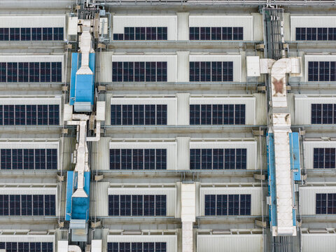 Aerial view of solar panels and industrial ventilation systems on a factory rooftop in San Giovanni Valdarno, Tuscany, Italy.