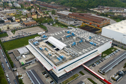 Aerial view of a large industrial facility with complex rooftop ventilation systems and parking lots in San Giovanni Valdarno, Tuscany, Italy.