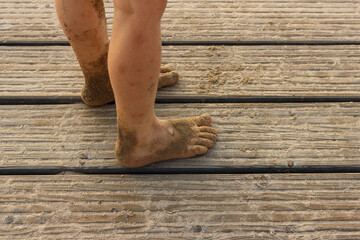 Bare feet of child covered with sand on wooden pier in summer © Iryna Miadzvedzeva