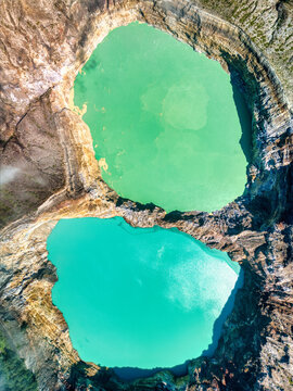 Aerial view of the vibrant turquoise and green volcanic crater lakes of Kelimutu National Park surrounded by steep rocky walls in Detusoko, East Nusa Tenggara, Indonesia.