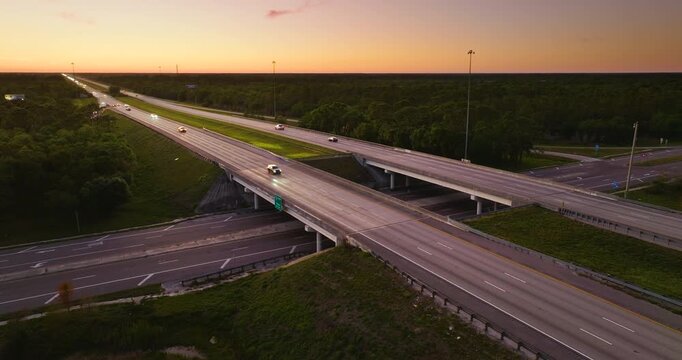 American highway bridge and exit lanes forming rural interchange with continuous vehicle movement at sunset