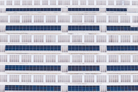 Aerial view of rows of solar panels installed on a large industrial warehouse roof with a geometric pattern Leccio, Toscana, Italy.