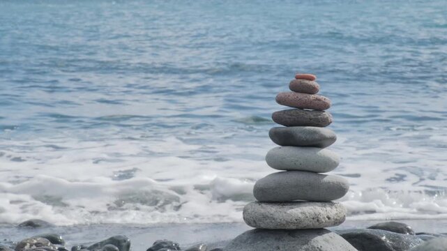 beach with cairn rocks, zen-like pebbles stacked in balanced pyramid against ocean waves, Balanced stones on beach, Meditation and mindfulness, harmony, travel, and serenity coastal retreats