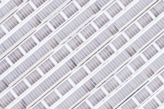 Aerial view of diagonal rows of a large greenhouse roof with glass panels and white structural frames in Leccio, Toscana, Italy.