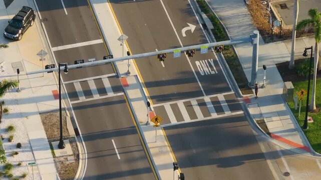 Downtown Sarasota street life during rush hour, with pedestrians crossing at signalized intersection, vehicles waiting in lanes, and city energy filling the scene.