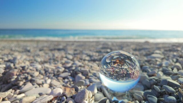 Crystal ball reflecting pebbles on a sunny mediterranean beach