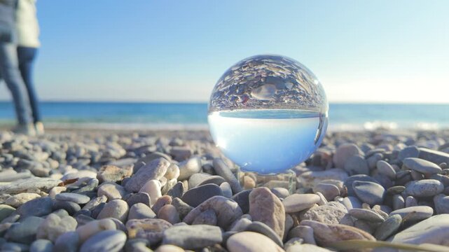 Crystal ball reflecting the sea on a sunny mediterranean pebble beach