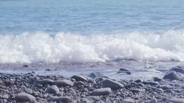 Black Volcanic sand beach and blue water ocean in Madeira, coast Portugal, Atlantic waves sparkle in sun, warm Gulf Stream water flows, peaceful energy, marine life