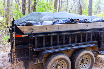 Truck with covered load parked near wooded area in rural setting