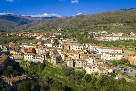 Aerial view of Loro Ciuffenna with its historic stone buildings and terracotta rooftops nestled against lush green hills in Loro Ciuffenna, Tuscany, Italy.