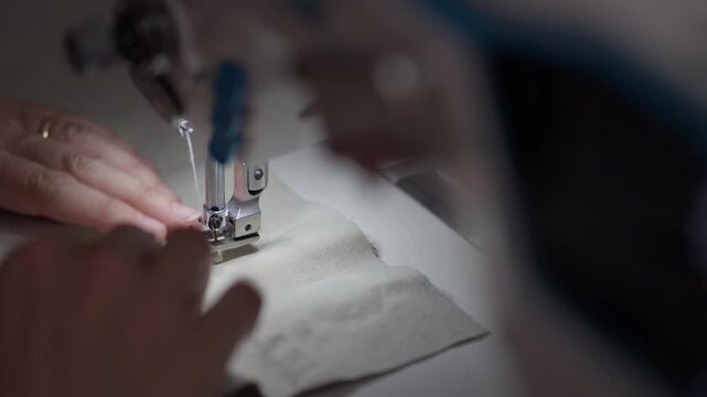 Hands gracefully guide fabric through a sewing machine, bringing material to life as stitches form patterns. Each movement captures the essence of craftsmanship and artistry.