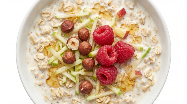 Top view of Birchermuesli bowl with oats, fresh raspberries, hazelnuts and apple on white background.