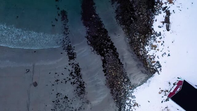 Drohne steigt auf &uuml;ber arktischer K&uuml;ste mit Fischerhaus Strand und t&uuml;rkisblauem Meer in Nordnorwegen