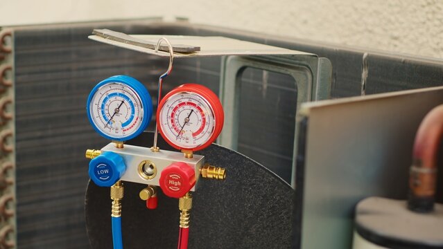 Zoom out shot of broken pressure measurement device used for checking hvac system freon pressure, in need of repair. Set of manifold meters showing high or low refrigerant levels