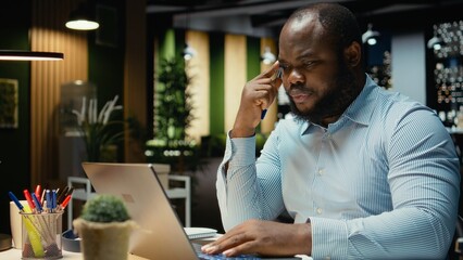 Black man consultant enjoying a cup of coffee to stay awake late at night, handling administrative tasks in the corporate space. Proofreading and writing at night with a caffeine drink. © DC Studio