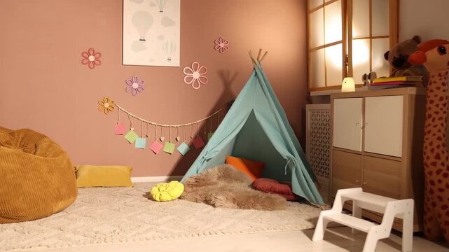 Colorful paper notes and beautiful decor hanging on brown wall near toy wigwam in stylish children's room, camera moving forward. Interior design