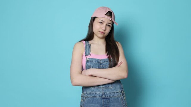 Teenage girl posing on light blue background, camera moving in