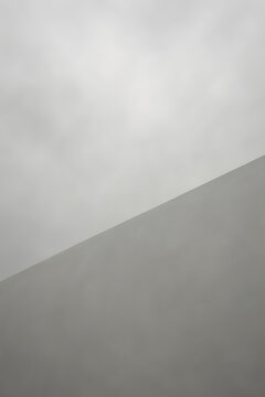 Minimalist geometric abstraction of a concrete wall against a grey sky