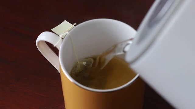 Video of pouring boiling water on turmeric chai tea in a tea bag in a cup.