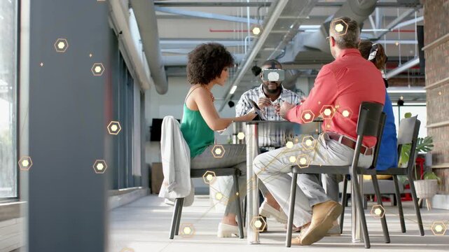 Team of four around table, center man donning VR headset, navigating hexagon UI for technology demo