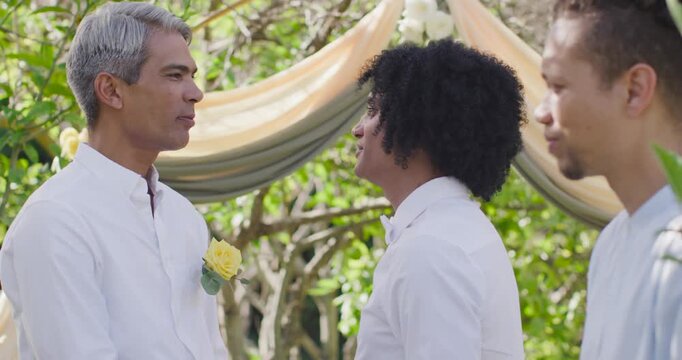 African American male partners exchanging vows after officiant prompt, standing under draped arch
