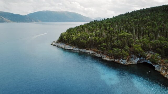 Secluded coastline with cypress tree forest and sea cave in summer Kefalonia, Greece